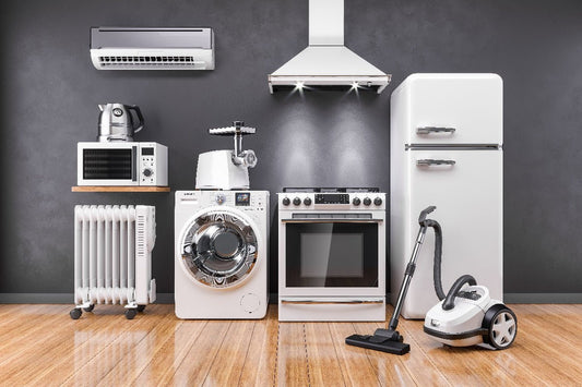 Collection of household appliances including an air conditioning unit, range hood, microwave oven, kitchen mixer, electric stove, washing machine, refrigerator, and vacuum cleaner before removal by Wilk's Junk Service.