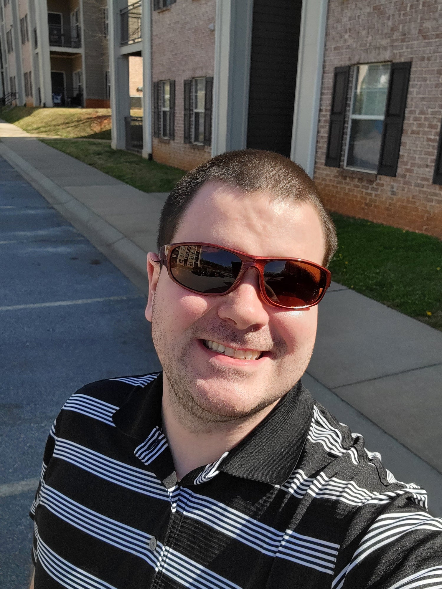 Brandon Costanza taking a selfie in front of an apartment complex, representing Wilk's Junk Service and their commitment to professional junk removal services.