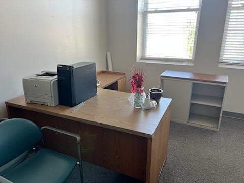 Office space with a large wooden desk, desktop computer, printer, and green chair, ready for removal by Wilk's Junk Service.