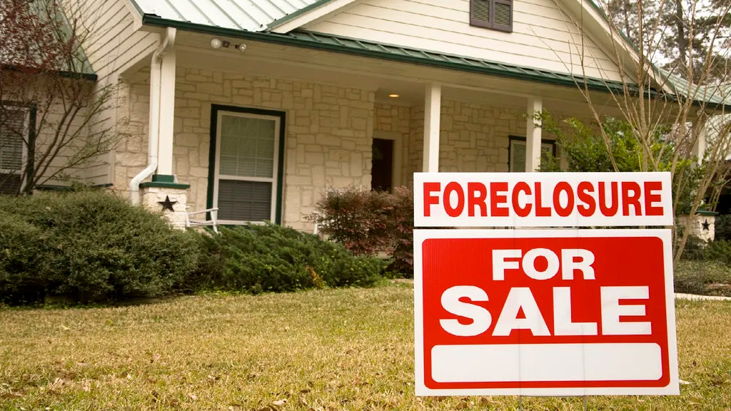 Foreclosure For Sale sign in front of a house with a stone facade and covered porch. Showcasing Wilk's Junk Service's foreclosure cleanout expertise.