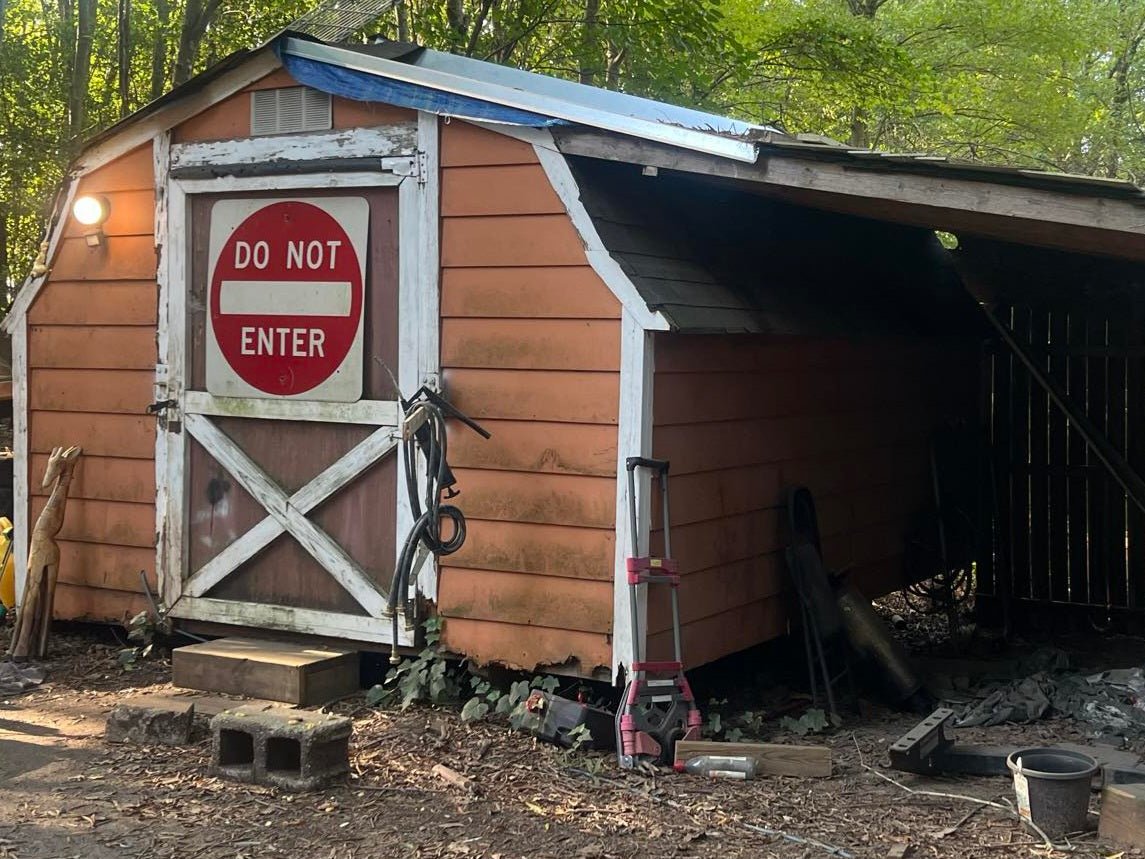 A dilapidated wooden shed, partially collapsed, with a "DO NOT ENTER" sign on the front door. This image represents a light demolition scenario for Wilk's Junk Service.