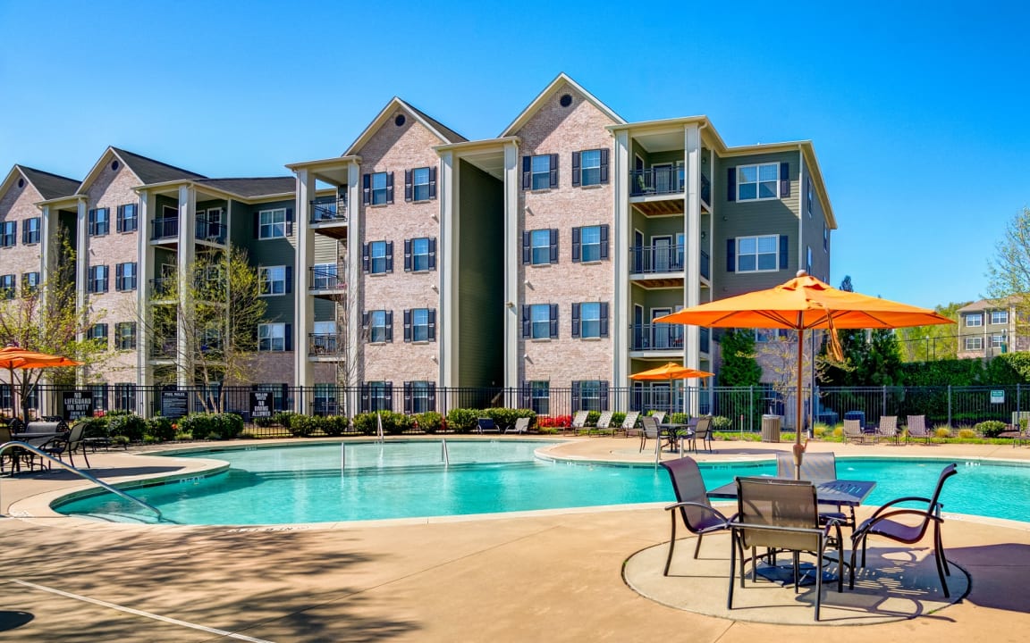 Freshly cleaned apartment complex with a sparkling pool, organized lounge chairs, and bright orange umbrellas, highlighting a tidy, move-in-ready property after junk removal.