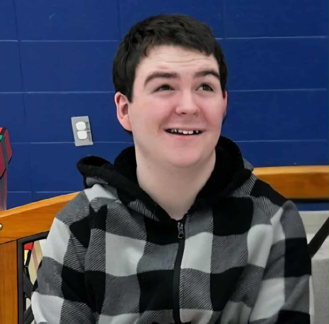 Ricky, a 17-year-old boy from Roebuck, SC, smiling while wearing a black and gray checkered hoodie, featured as the October 2025 Junk for Joy sponsored child.