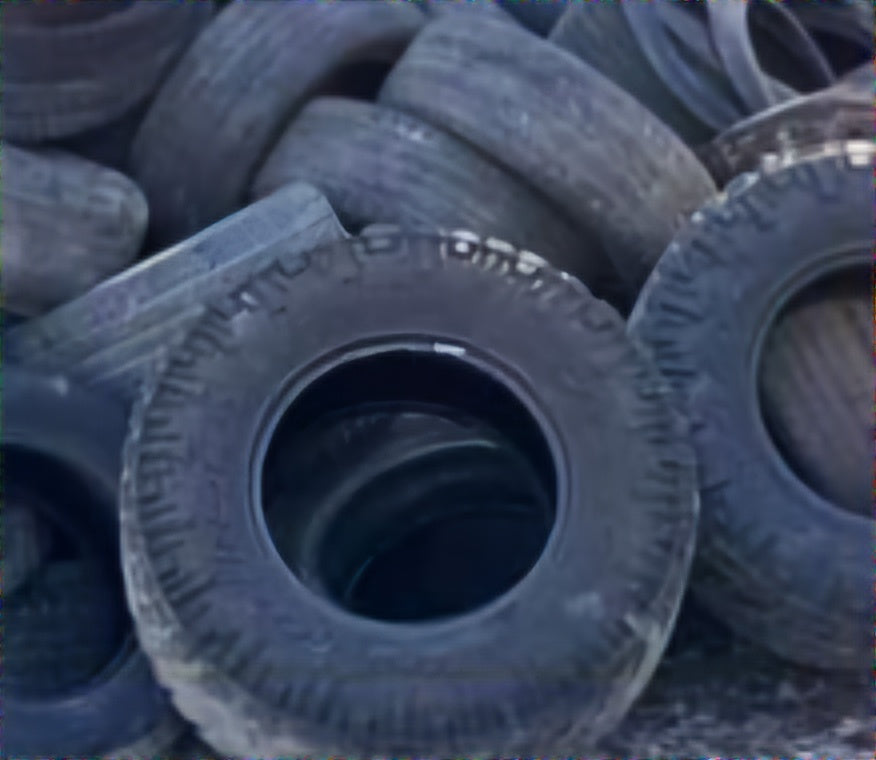 A pile of used and discarded tires of various sizes, collected for removal by Wilk's Junk Service. The tires are in a disorganized heap, with visible treads indicating wear and outdoor storage conditions.
